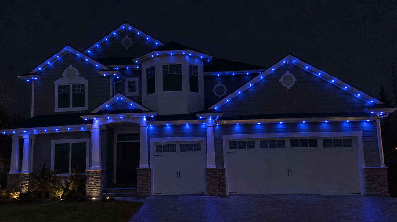 Ottawa two-story home with permanent blue track lighting along the rooflines and garage at night